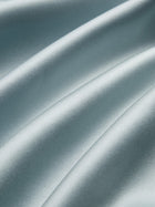 Close-up of smooth, light blue satin fabric with gentle folds and a shiny finish, evoking the Social Queen Floral Embroidered Beaded Jacket accented with hand-embroidered floral motifs.