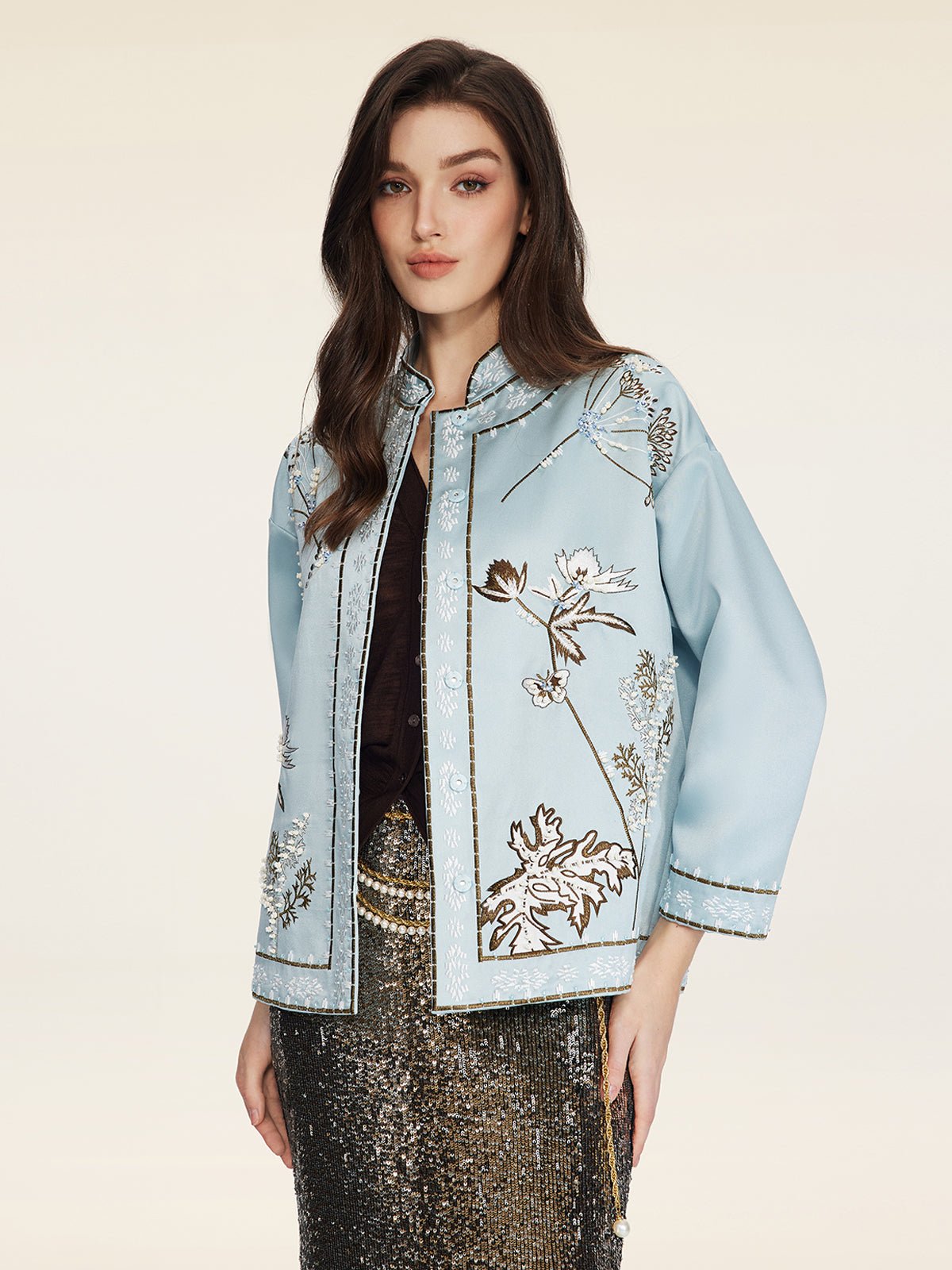A woman models the Social Queen Floral Embroidered Beaded Jacket over a black top and gold sequin skirt, set against a plain light background.