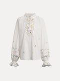 The Social Queen Floral Embroidered Cotton Blouse features a white long sleeve design with pastel embroidery, ruffled cuffs, and a tie-neck detail.