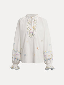 The Social Queen Floral Embroidered Cotton Blouse features a white long sleeve design with pastel embroidery, ruffled cuffs, and a tie-neck detail.