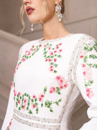 A woman showcases the Social Queen Floral Embroidered Crystal Dress, featuring pink and green floral embroidery with silver accents, paired with large pearl earrings—ideal for an elegant evening event.