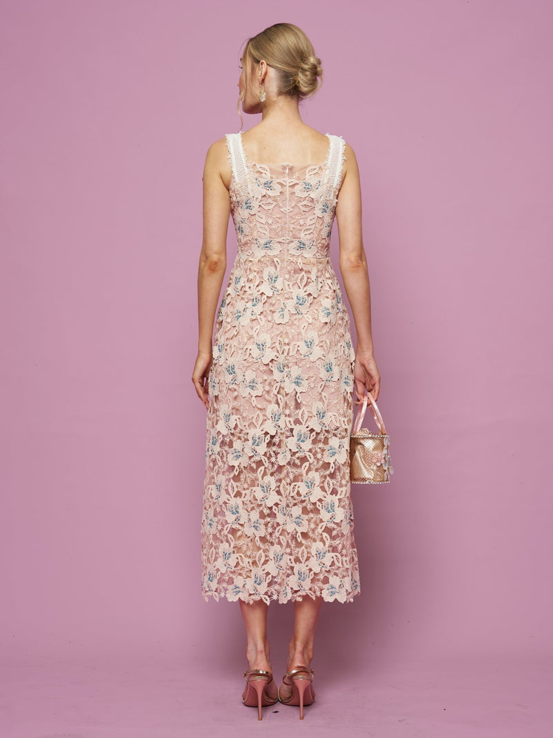 A woman stands with her back to the camera against a pink background, wearing the Social Queen Floral Embroidered Cutout Lace Dress and heels, holding a small purse.