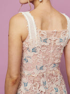 A person wearing the Social Queen Floral Embroidered Cutout Lace Dress—sleeveless, pink, with blue floral embroidery—stands against a light purple background.