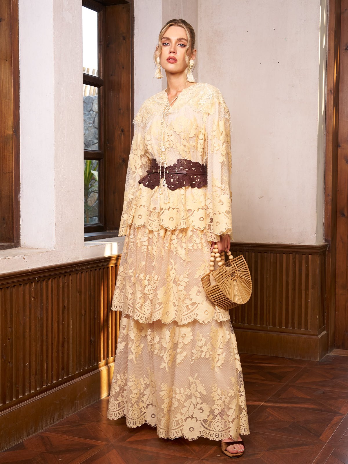 Indoors, a woman models the Social Queen Floral Embroidered Lace Layered Skirt, styled with a dark belt and wooden handbag near large windows—an elegant wedding guest look.