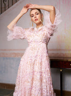 A woman poses indoors in the Social Queen Floral Embroidered Layered Tulle Dress, featuring light pink tulle, floral embroidery, and sheer ruffled sleeves—making it a romantic choice for a wedding guest.