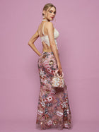 A woman stands against a pink background, wearing the Social Queen Floral Embroidered Sequin Mermaid Skirt and a white lace top, holding a small pink handbag while looking over her shoulder.