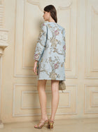 A woman stands indoors facing away, wearing the Social Queen Floral Embroidered Silk Jacquard Jacket, gold high-heeled sandals, and holding a small handbag.