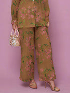 Model wears Social Queen Floral Embroidered Textured Wide-Leg Pants with gold heels and a decorative handbag, posing against a pink background.
