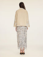 A woman faces away wearing Social Queen's Floral Embroidered Velvet Jacket and a long silver fringe skirt with black strappy heels, set against a plain light background.