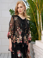 A blonde woman stands outside by a white wall and green plants, wearing the Social Queen Floral Embroidery 100% Mulberry Silk Tulle Blouse.