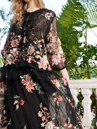 A woman stands outdoors near green plants and a white railing, wearing the Social Queen Floral Embroidery 100% Mulberry Silk Tulle Blouse.