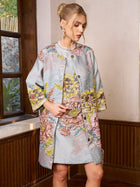 A woman stands indoors wearing the Social Queen Floral Jacquard Beaded Jacket and matching dress, her hair in an updo and hands resting on the jacket.
