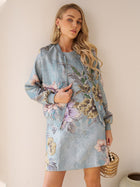 A woman stands against a beige wall in the Social Queen Floral Jacquard Dress, paired with a light blue floral-patterned jacket and a round beaded handbag—an elegant choice for wedding guests.