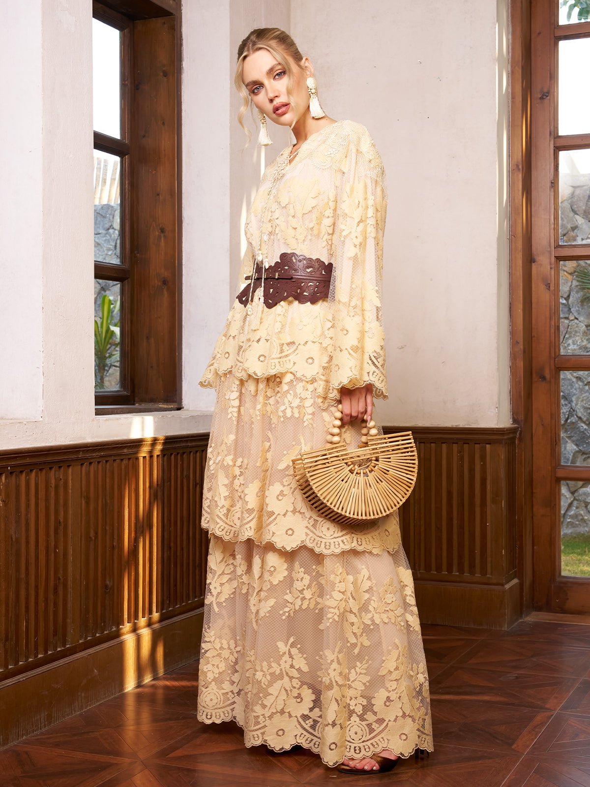 A woman wears the Social Queen Floral Lace Embroidered Blouse, featuring cream 3D floral embroidery and water-soluble lace, paired with a wooden handbag, standing indoors by large windows and wood paneling.
