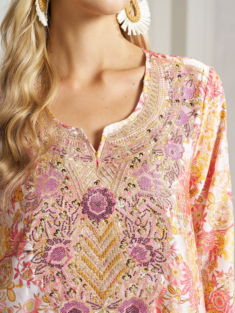 A woman wears the Social Queen Floral Print Beaded Dress, featuring a hand-beaded neckline with pink and gold embroidery, paired with white statement earrings.