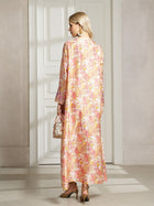 A woman stands indoors facing a white door, wearing the Social Queen Floral Print Beaded Dress and heeled sandals, holding a small transparent handbag, with her back to the camera.