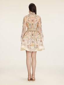 A woman stands facing away, wearing the Social Queen Floral Print Hand-Beaded Dress with sheer patterned tights and high heels, against a plain background.