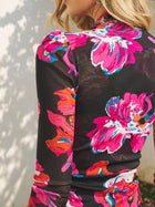 A woman with blonde hair wears the Social Queen Floral Print Knot Front Knit Dress, featuring large bright pink and orange patterns, while standing outdoors near a white wall.
