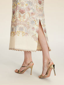 A person wearing the Social Queen Floral Print Midi Skirt with a side slit and gold high-heeled sandals stands against a light background.