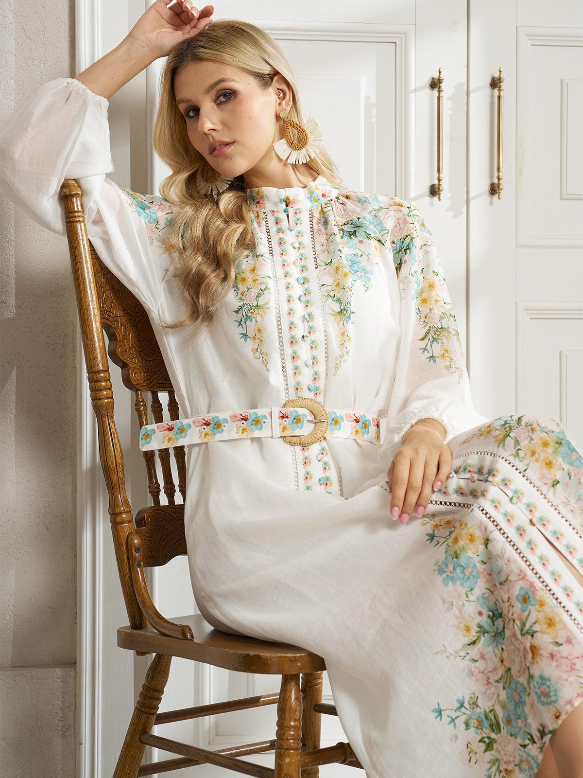 A woman in a Social Queen Floral Printed Stand-Collar Dress sits on a wooden chair in a bright room, resting her arm on her head.