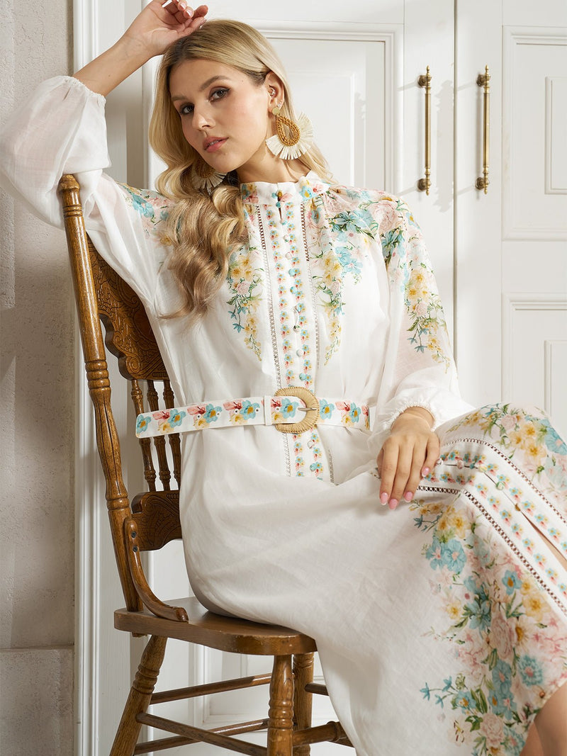 A woman in a Social Queen Floral Printed Stand-Collar Dress sits on a wooden chair in a bright room, resting her arm on her head.