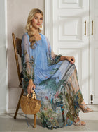A woman sits on a wooden chair in front of white paneled doors, wearing the Social Queen Garden-Inspired Print Pleated Dress and holding a woven bamboo handbag.
