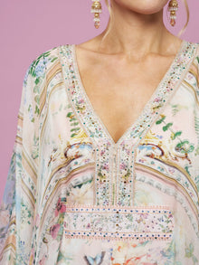 A close-up of a woman wearing the Social Queen Garden Print Silk Dress against a pink background, with earrings visible.