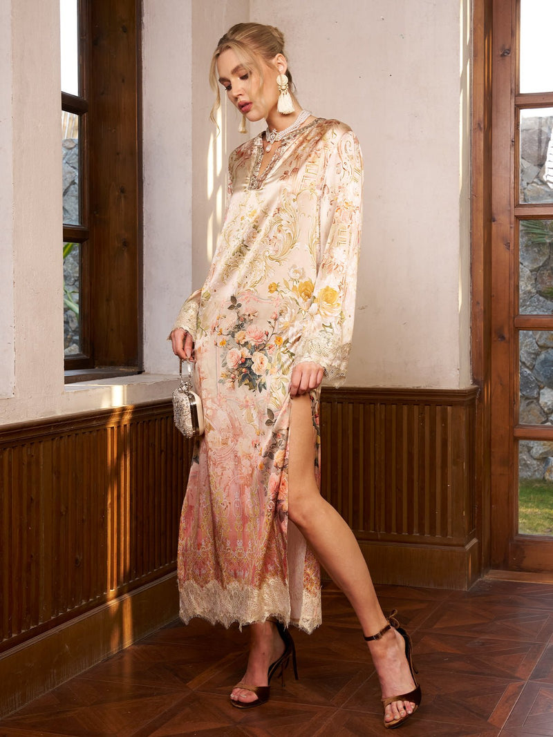 A woman in the Social Queen Garden Print Silk Dress with Lace Trim stands indoors, holding a small purse and wearing high-heeled sandals and statement earrings.