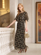 A woman wears the Social Queen Gilded Beaded Cape Dress indoors by a white railing, holding a small gold purse and sporting metallic heels.