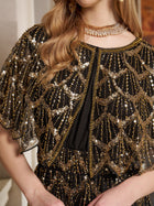 A woman in the Social Queen Gilded Beaded Cape Dress, featuring gold and silver sequins, a sheer overlay, and a gold choker necklace—ideal for an elegant evening event.