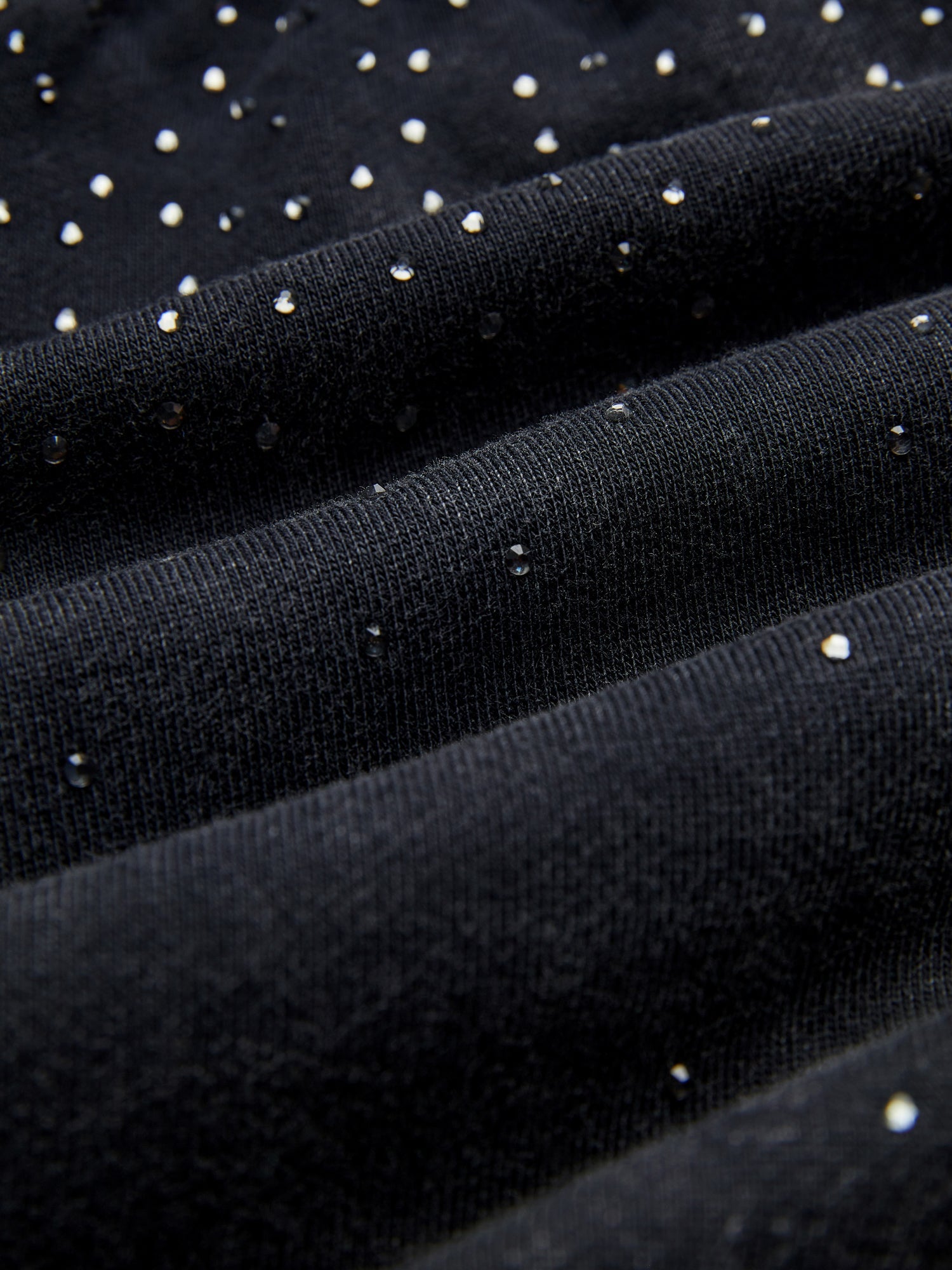 Close-up of Social Queen’s Gradient Rhinestone Wide-Leg Pants, showcasing their textured black fabric with small, shiny silver studs scattered throughout.