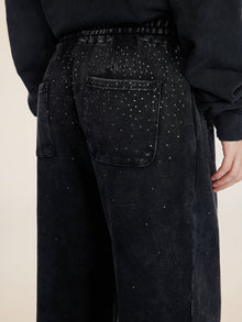 A person wearing Social Queen Gradient Rhinestone Wide-Leg Pants featuring an elastic waist, back pockets, and scattered rhinestone embellishments.