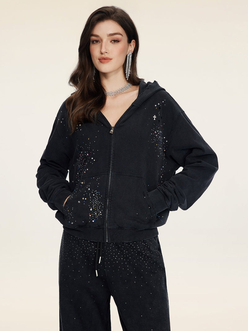 A woman models the Social Queen Hand-Applied Rhinestone Washed Hoodie with matching pants, both in black and embellished with sparkling hand-applied rhinestones, set against a plain light background.