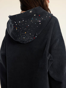 A person seen from behind wears the Social Queen Hand-Applied Rhinestone Washed Hoodie, featuring multicolored beads and hand-applied rhinestones on the hood.