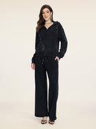 A woman wears the Social Queen Hand-Applied Rhinestone Washed Hoodie with matching wide-leg pants, both featuring hand-applied rhinestones, styled with black heeled sandals.