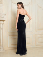 A woman stands indoors facing away, wearing the Social Queen Hand-Applied Silver Crystal Baroque Velvet Gown near a decorative wall and fireplace.