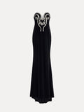 The Social Queen Hand-Applied Silver Crystal Baroque Velvet Gown is a strapless, fitted evening dress with hand-beaded silver crystal swirl details on the chest and a floor-length skirt.