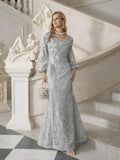 A woman in the Social Queen Hand-Beaded Lace Mermaid Dress stands on a marble staircase by a sculpture, holding a handbag and wearing statement jewelry.