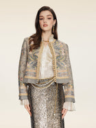 A woman faces forward in a Social Queen Hand-Beaded Printed Jacket, styled with a ruffled blouse, long metallic sequin skirt, and gold accessories against a neutral background.