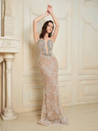 A woman in the Social Queen Hand-Beaded Sequin Embroidered Cocktail Gown stands with arms raised above her head before a decorative cream-colored wall and fireplace.