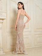 A woman stands indoors, facing slightly away, wearing the Social Queen Hand-Beaded Sequin Embroidered Cocktail Gown—a sleeveless, floor-length nude dress with silver sequins and elegant lace trim.