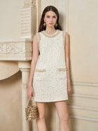 A woman wears the Social Queen Hand-Beaded Silk Wool Embossed Dress, paired with a matching pearl-accented bag and statement earrings, standing indoors and looking directly at the camera.