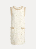 The Hand-Beaded Silk Wool Embossed Dress by Social Queen is a sleeveless cream mini dress featuring pearl trim, gold bead embellishments, two front pockets, and a round neckline.