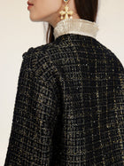A person wearing the Social Queen Hand-Beaded Tweed Fringe Jacket, featuring black-and-gold tweed with a metallic collar and large star-shaped earrings, shown from the side.