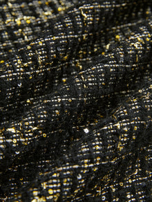 Close-up of hand-beaded detailing on Social Queen's Hand-Beaded Tweed Fringe Jacket, featuring gold and white threads and sequins forming a grid-like pattern on black-and-gold tweed.