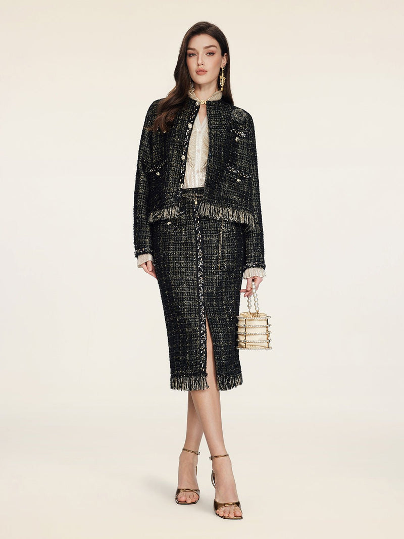A woman faces forward in a cropped silhouette, wearing Social Queen's Hand-Beaded Tweed Fringe Jacket over a white blouse, with strappy heels and a small handbag against a plain background.
