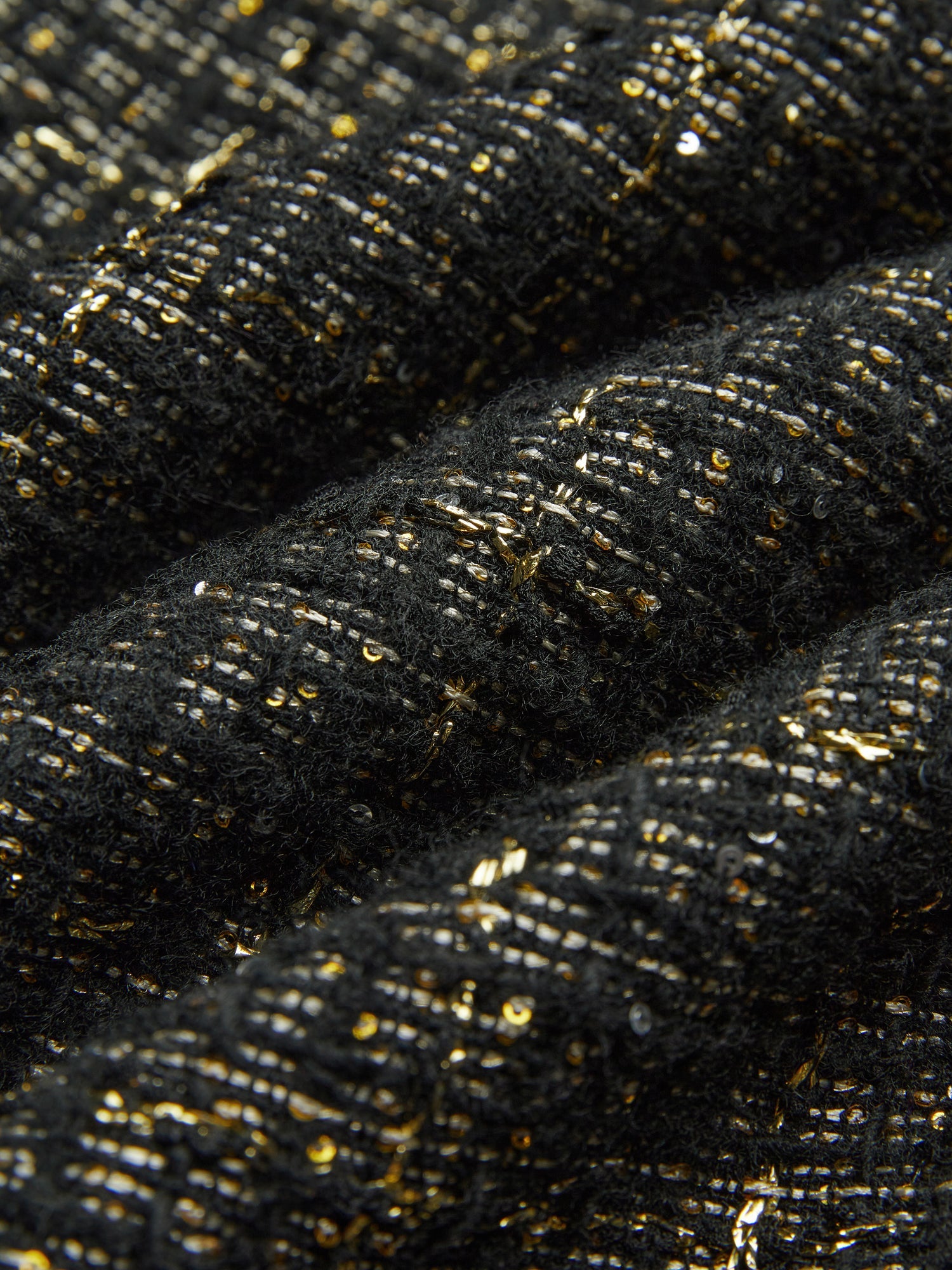 Close-up of Social Queen's Hand-Beaded Tweed Fringe Slit Skirt shows black-and-gold tweed fabric with gold metallic threads and small sequins woven throughout.