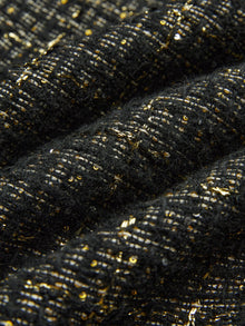 Close-up of Social Queen's Hand-Beaded Tweed Fringe Slit Skirt shows black-and-gold tweed fabric with gold metallic threads and small sequins woven throughout.