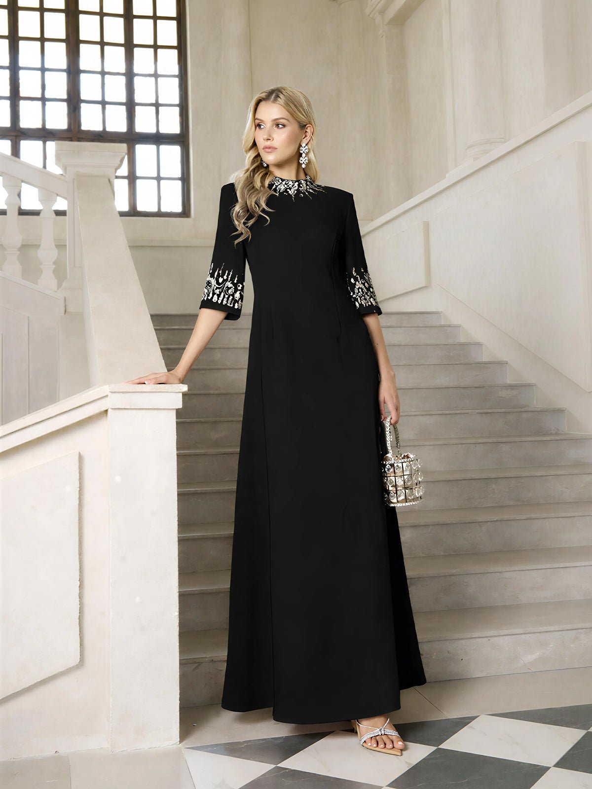 A woman stands on a staircase wearing the Social Queen Hand-Embellished A-Line Dress, featuring decorative accents on the sleeves and neckline, and holds a small handbag.
