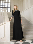 A woman stands on a staircase wearing the Social Queen Hand-Embellished A-Line Dress, featuring decorative accents on the sleeves and neckline, and holds a small handbag.
